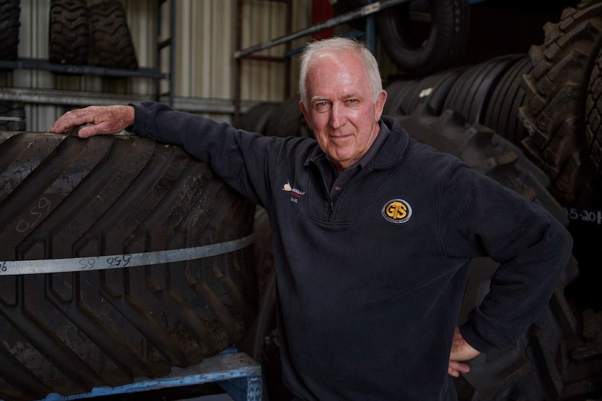 A man leaning on a stack of tyres in a tyre shop