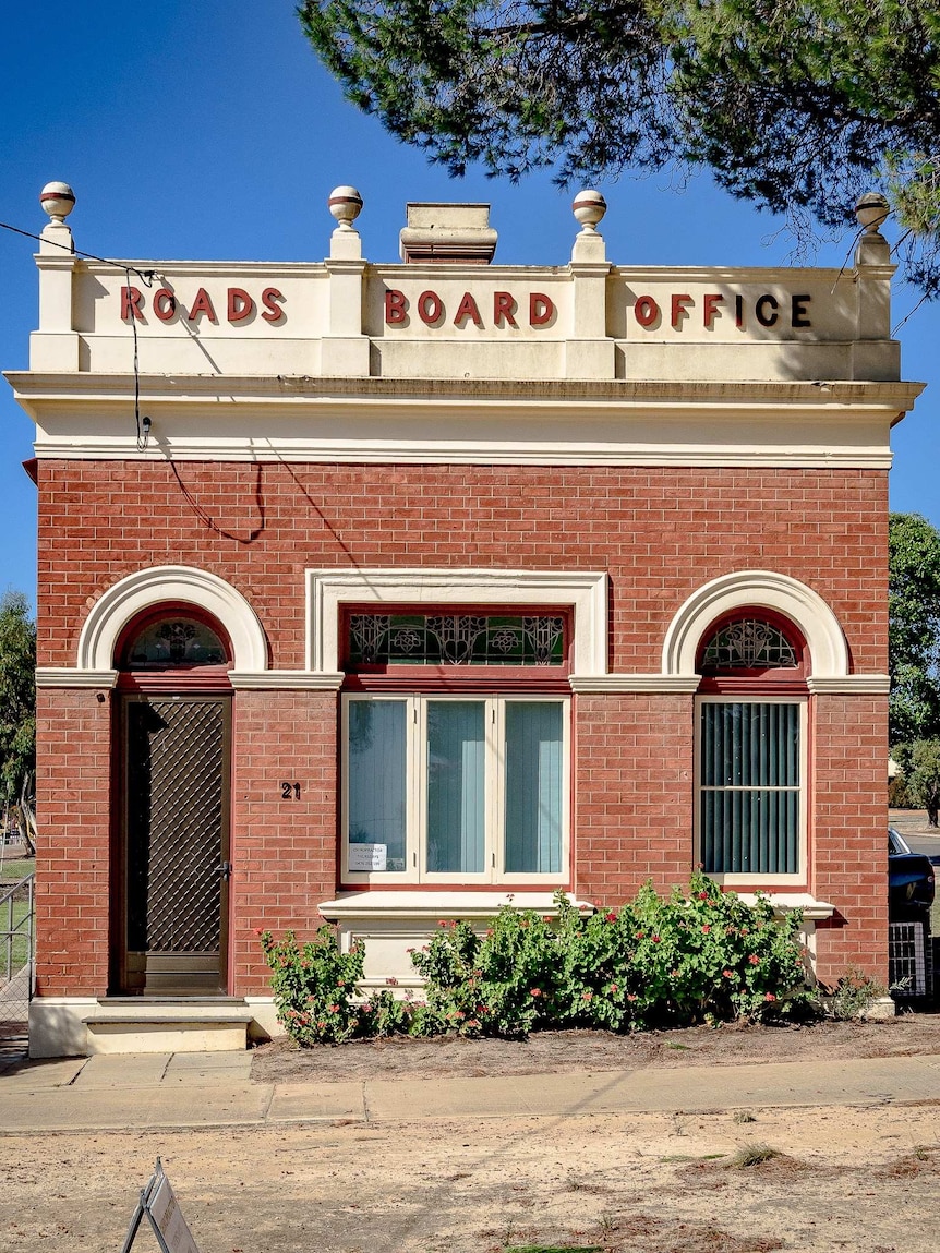 A small brick building with part of a tree on the right