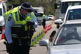 A policeman stands beside a car examining the driver's wallet.