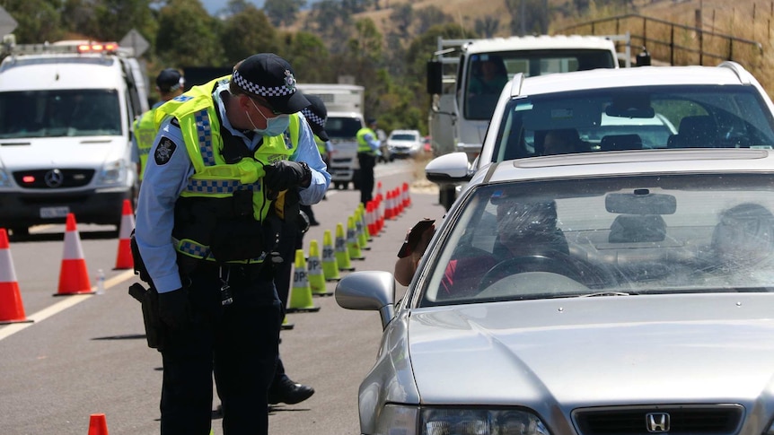 A policeman stands beside a car examining the driver's wallet.