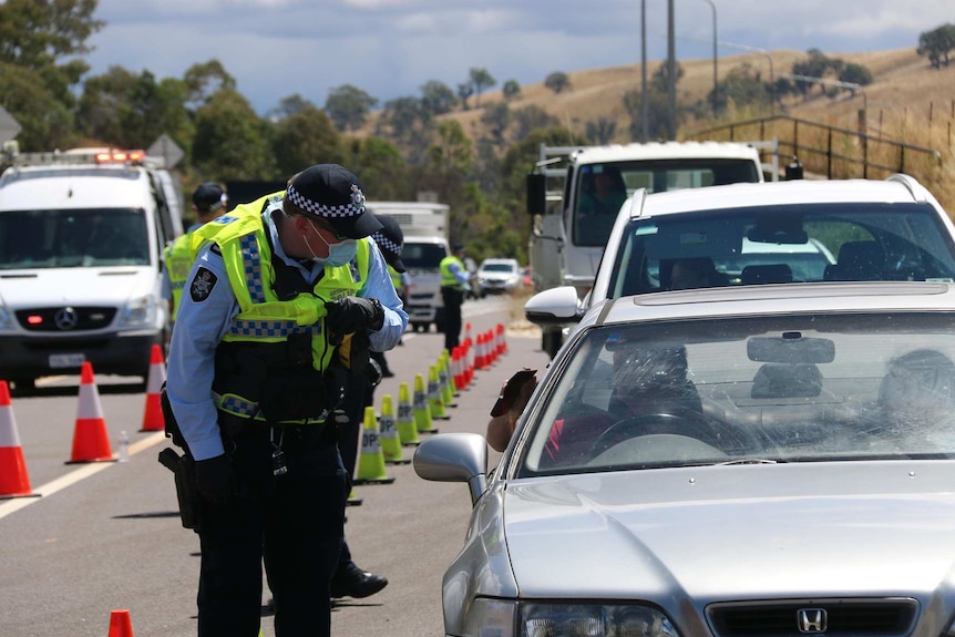 A policeman stands beside a car examining the driver's wallet.