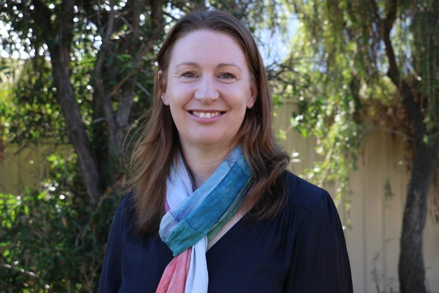 A woman wearing a coloured scarf smiles at a camera