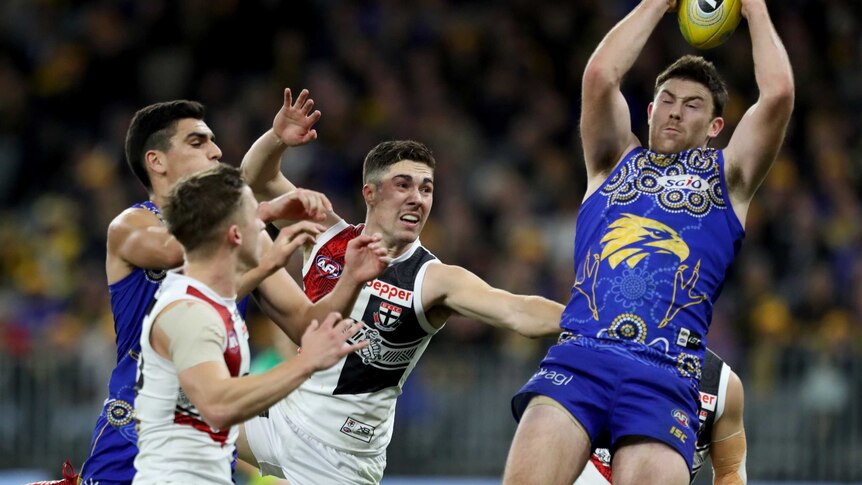 West Coast Eagles defender Jeremy McGovern marks a yellow football in front of a pack of other AFL players.