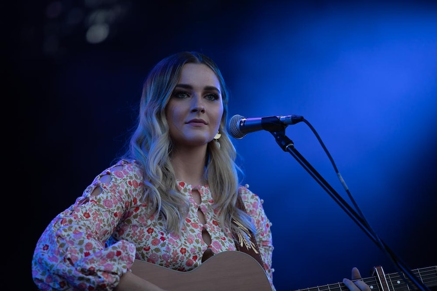 A woman getting ready to sing on a festival stage stares out to the audience