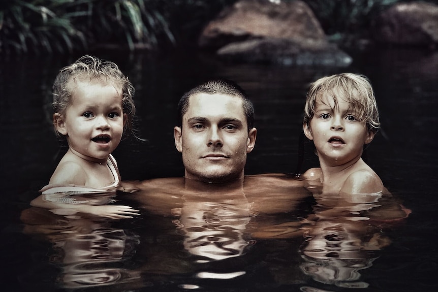 Nicholas Couldwell and two children swim in a river.
