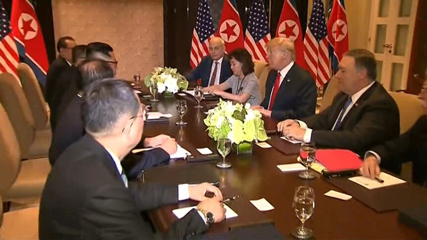 Donald Trump and his advisers sit opposite Kim Jong-un and his advisers at a table.