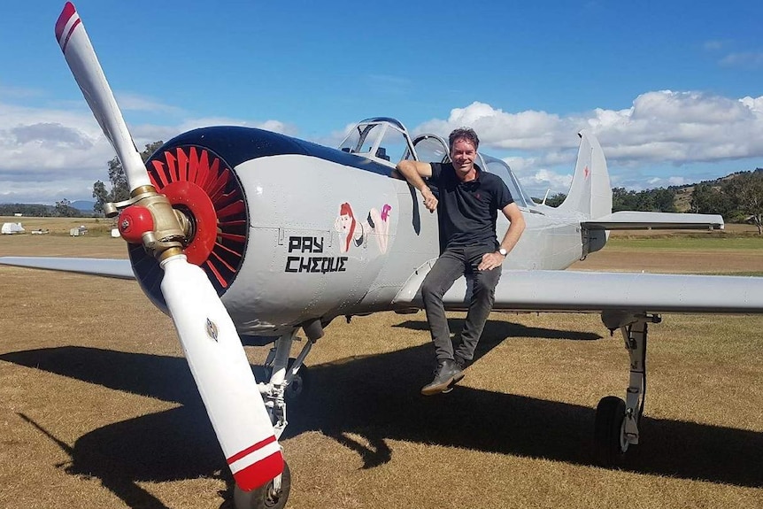 A man sitting on the wing of a small airplane