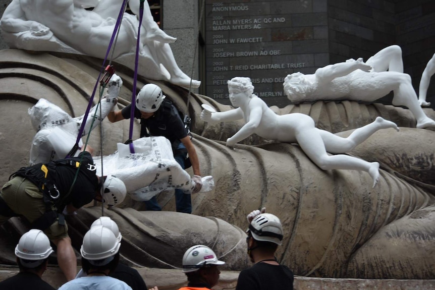 Workers carefully position a sculpture on the work.