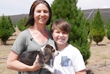Peta and Eli hold their beagle puppy in front of pine trees