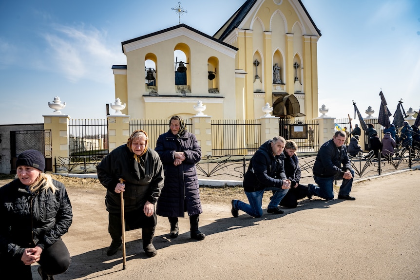 Villagers kneel on the path in front of the church as the coffin arrives. 