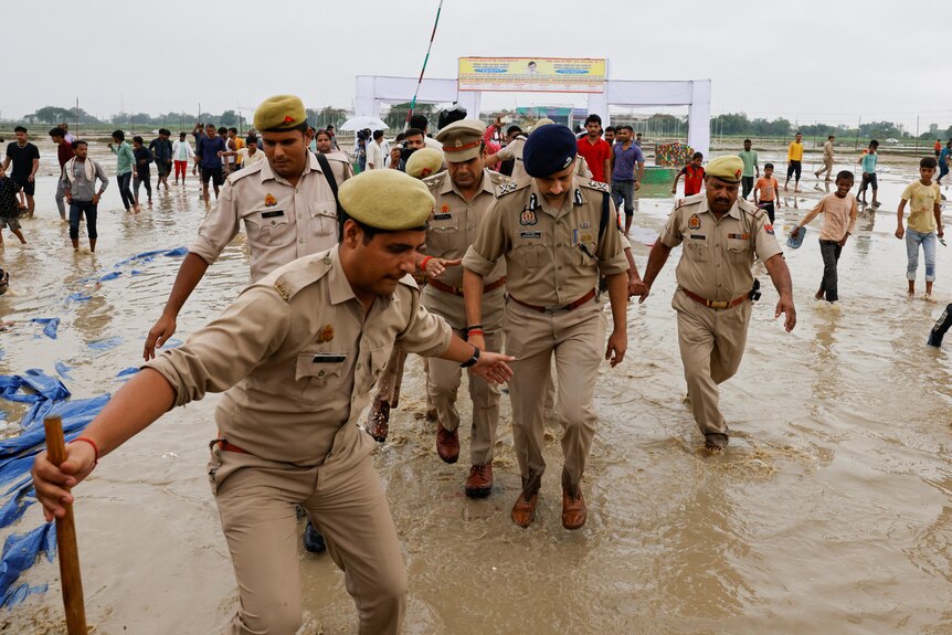 Police officers walk at the site where believers had gathered for a Hindu religious congregation.