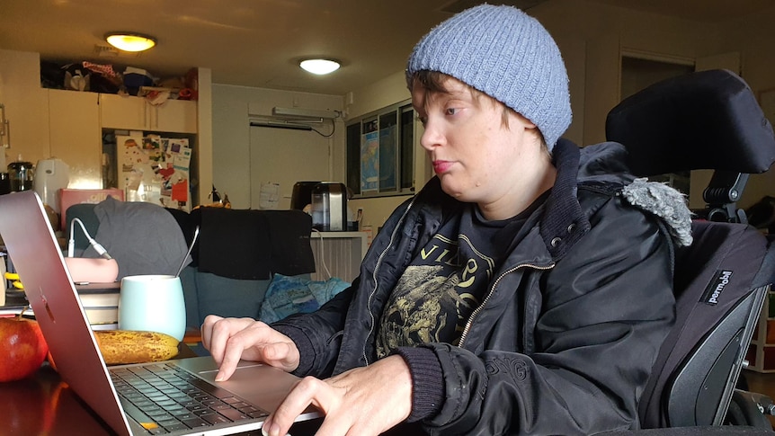 A woman wearing a beanie using a laptop computer