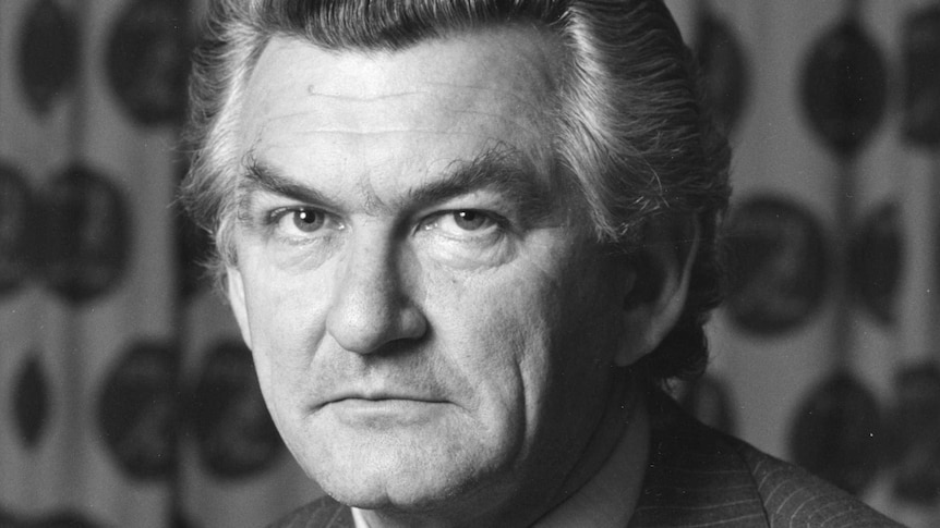 Bob Hawke, wearing pinstripe suit and tie, looks at the camera, patterned curtain in background.