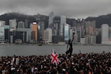 Thousands of Hong Kong protesters carry a British flag by the harbour.