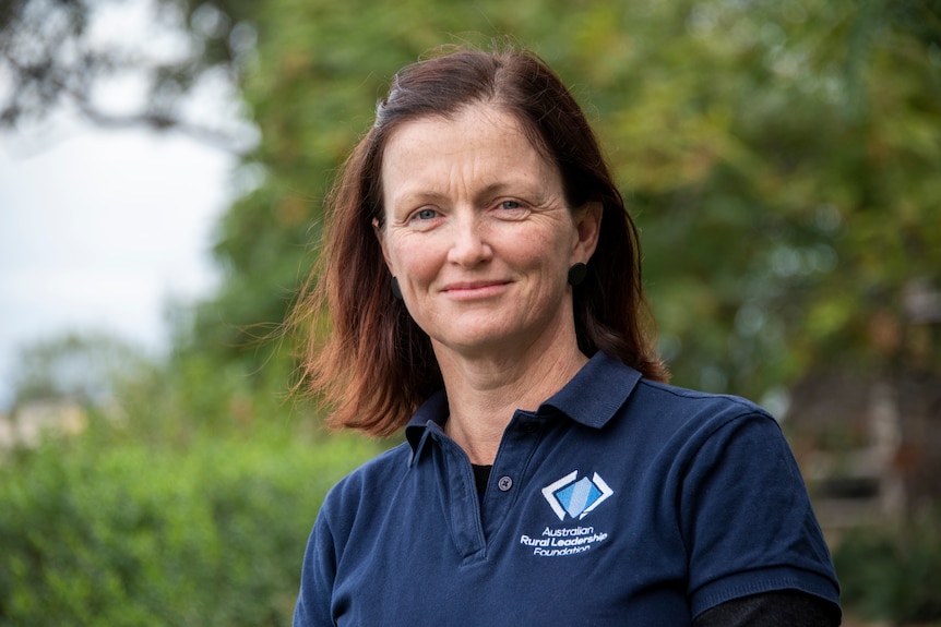 A woman in a navy polo smiles at the camera