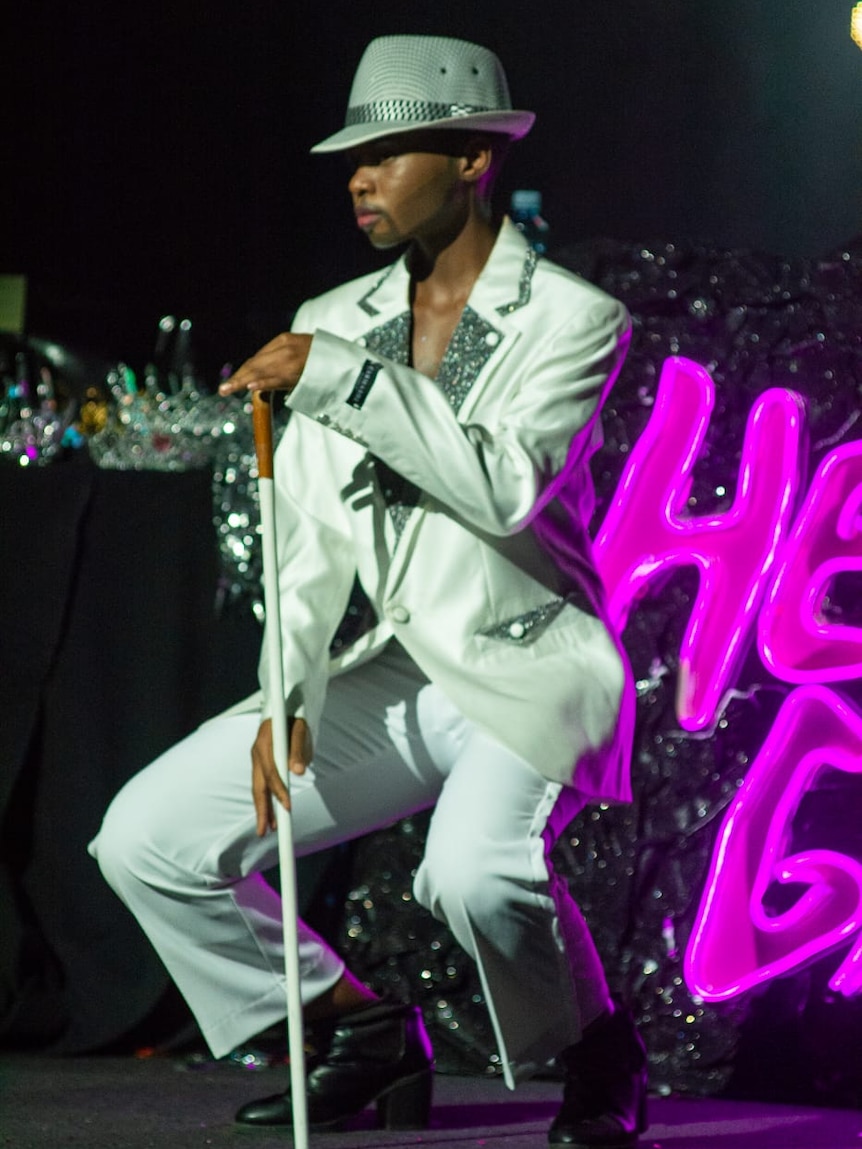 Ani performs on stage in a white suit.