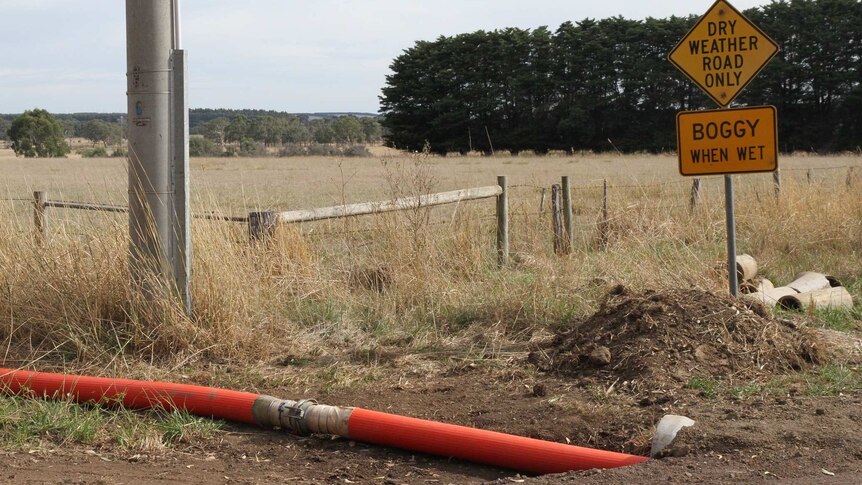 An orange pipe runs near a road sign that says "Dry Weather Road Only - Boggy When Wet".