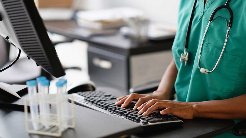 A doctor with their hands on a computer keyboard.