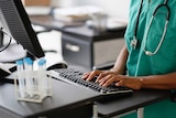 A doctor with their hands on a computer keyboard.