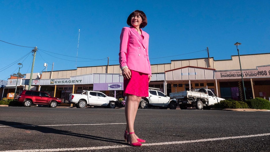 A woman wearing all pink stands in a small rural town.