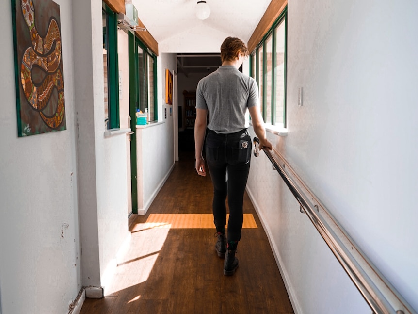 Woman walking down hallway with natural sunlight shining through