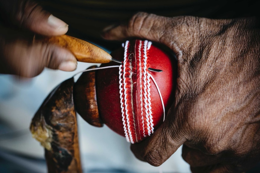 Hand stitching cricket ball.
