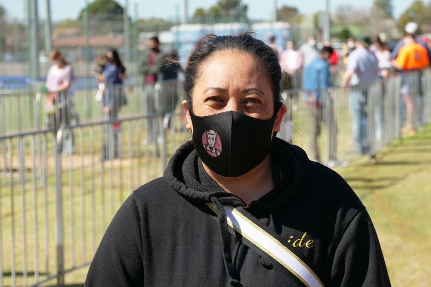 A woman with a mask and hoody looking at the camera