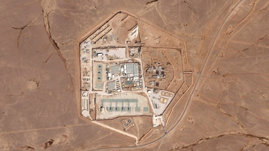 An aerial shot of a military compound with buildings and roads surrounded by desert