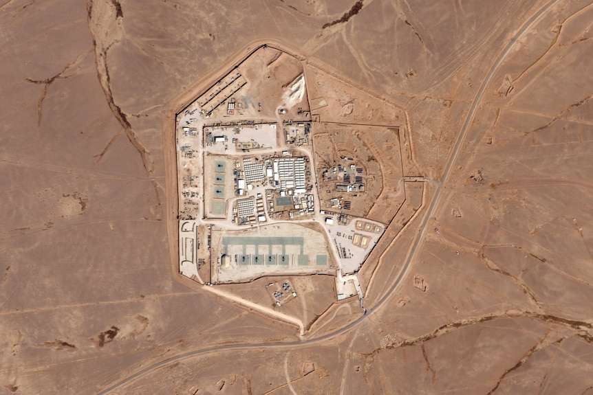 An aerial shot of a military compound with buildings and roads surrounded by desert