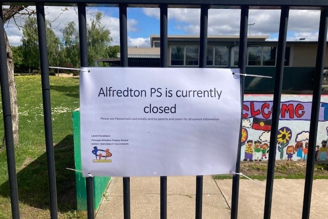 A sign on the gate of a primary school that is shut after a COVID exposure.