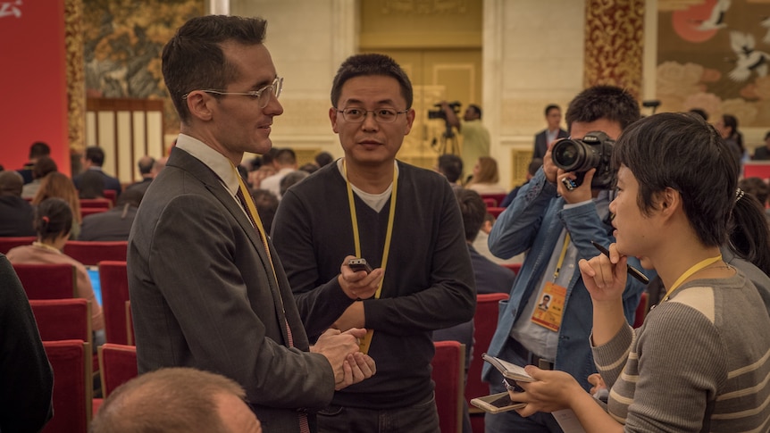 Foreign Correspondent Bill Birtles is interviewed by local Chinese media in a hotel ballroom.