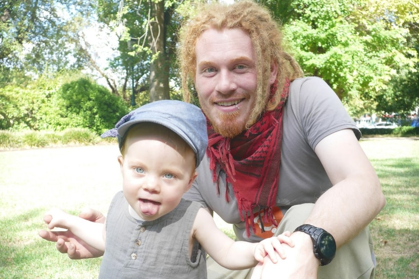 Computer programmer and cryptocurrency trader, James Cole, helping his toddler daughter, Leila, stand up in the park