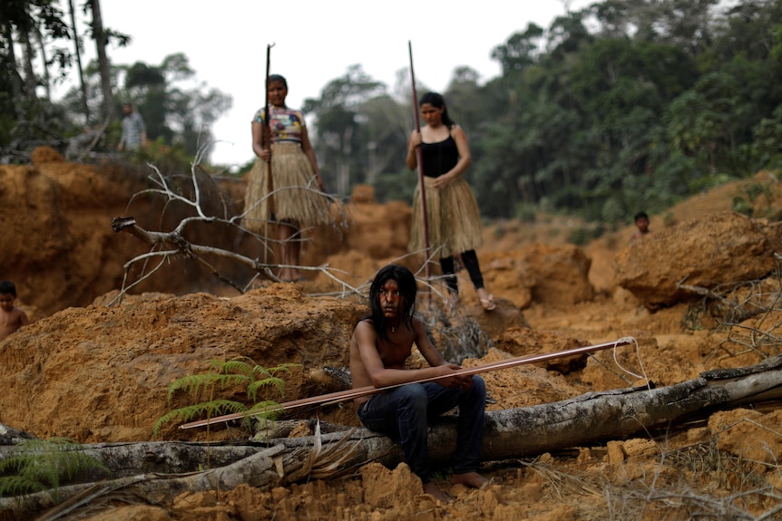 Indigenous people in Brazil sit in a deforested area of the Amazon rainforest on August 20, 2019.