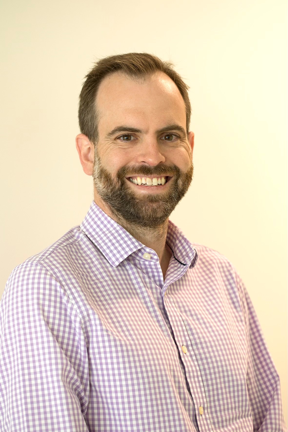 Um homem de meia idade com pelos faciais sorri para a câmera. 