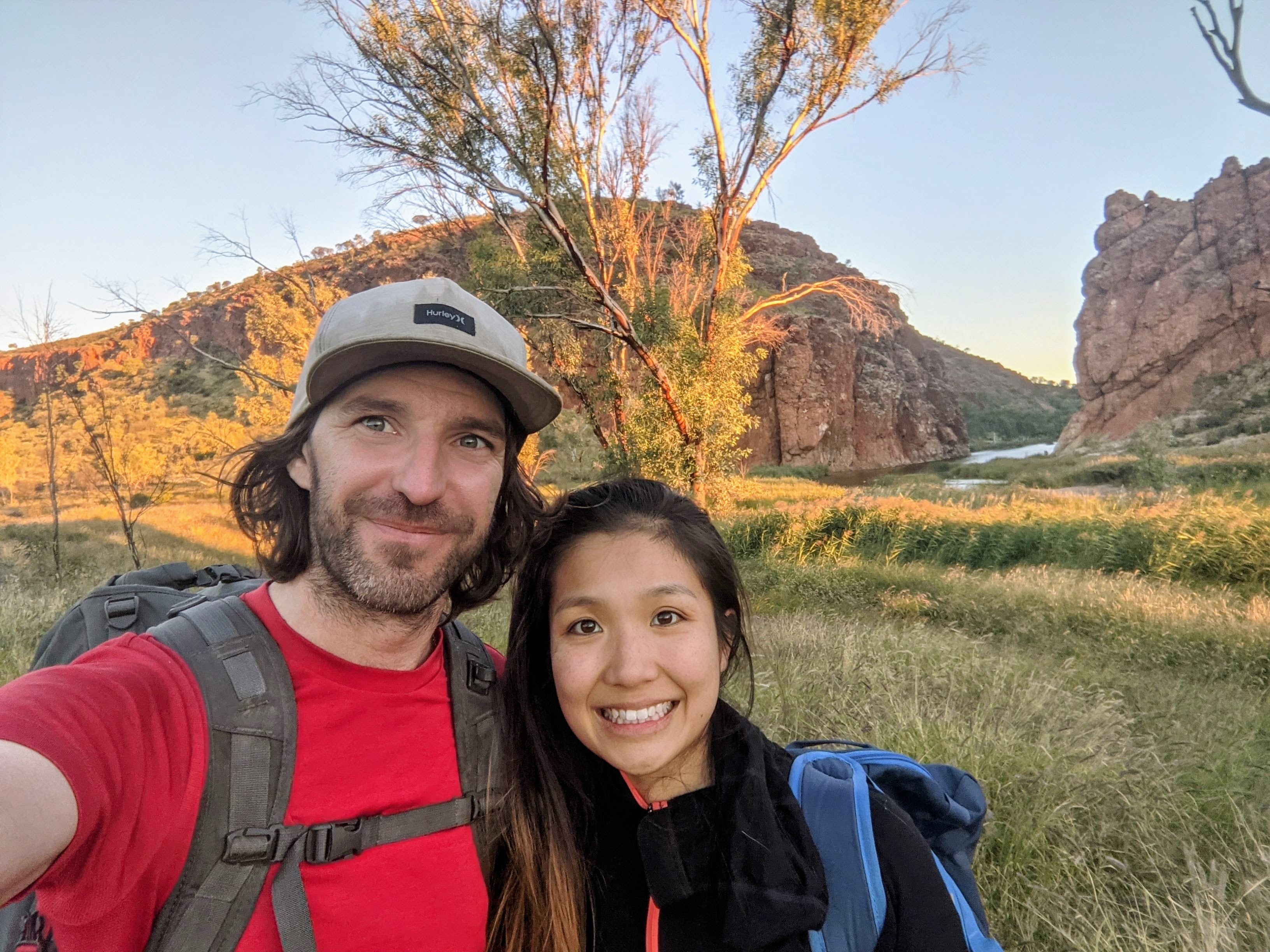 Winnie and Nelson hiking in a remote and rocky area with trees behind them.