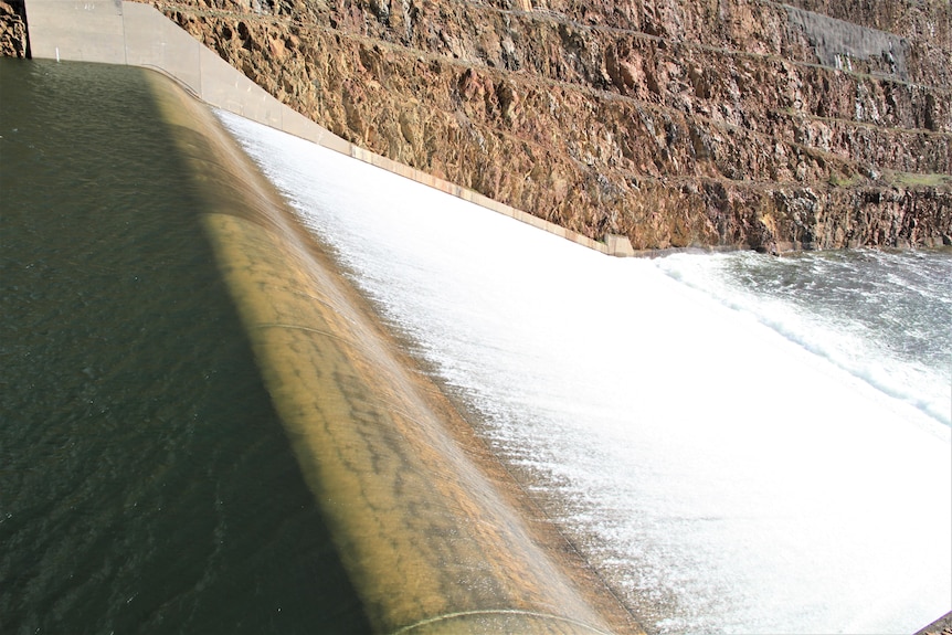 Water flows over a dam spillway.