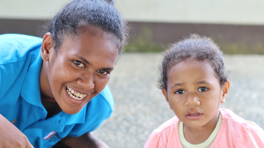 Tiyana smiles at the camera with her two-year-old daughter who looks slightly puzzled.