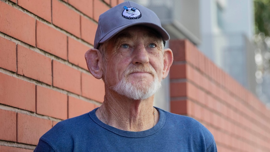 A man in a hat looks upwards away from the camera.