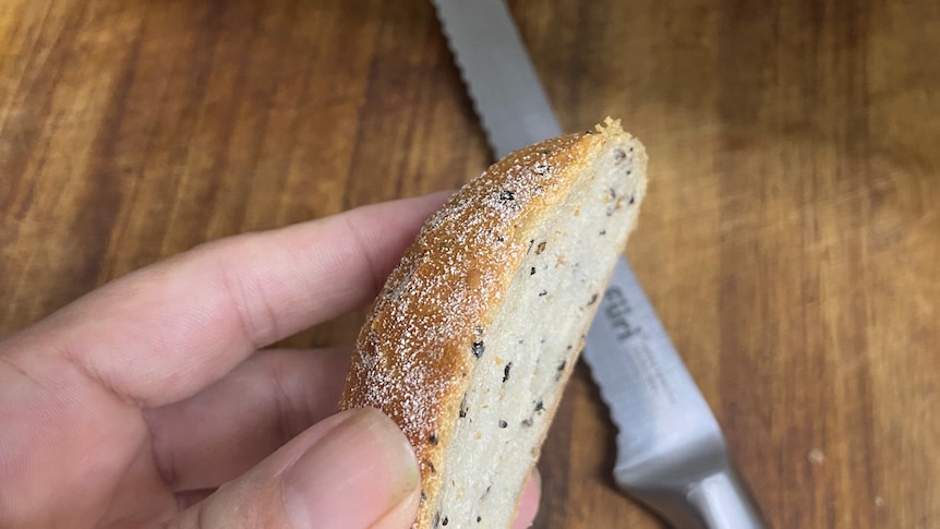 The heel of a loaf of bread being held over a cutting board