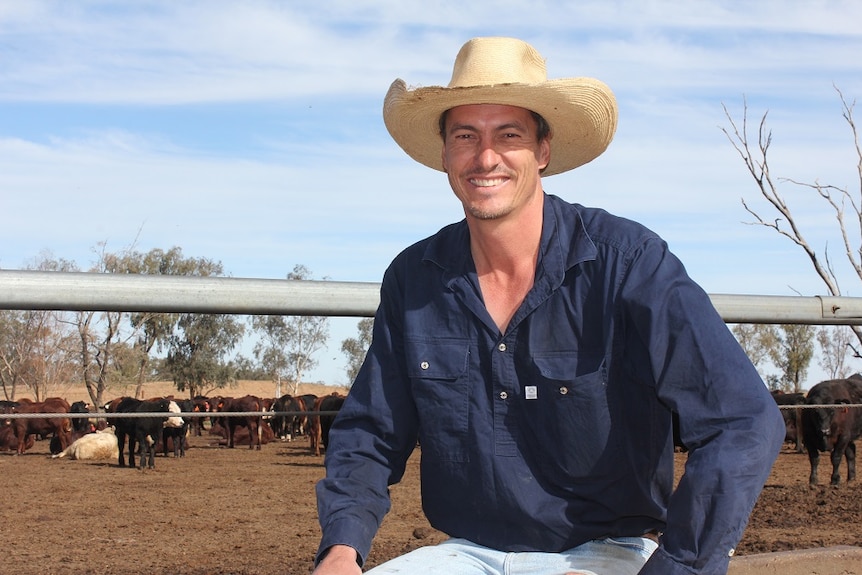 Michale MacCue sits in front of cattle in a feedlot.