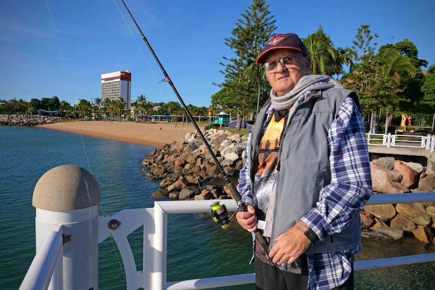 Terry Jackson wears a scarf and fleece jacket while fishing from Townsville's Strand jetty.