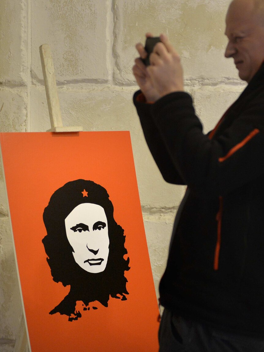 A visitor stands next to an artwork depicting Russian President Vladimir Putin as Che Guevara.
