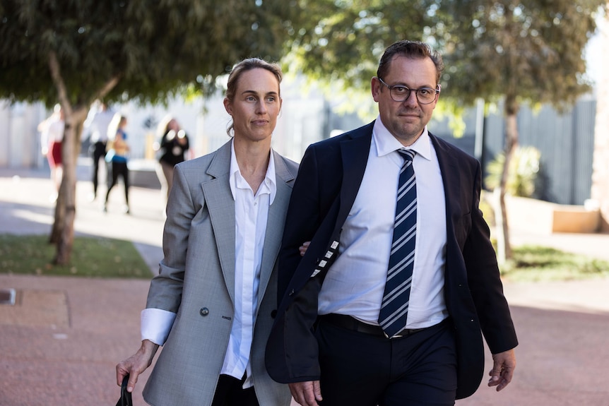 A man and a woman leave a courthouse after a trial.  