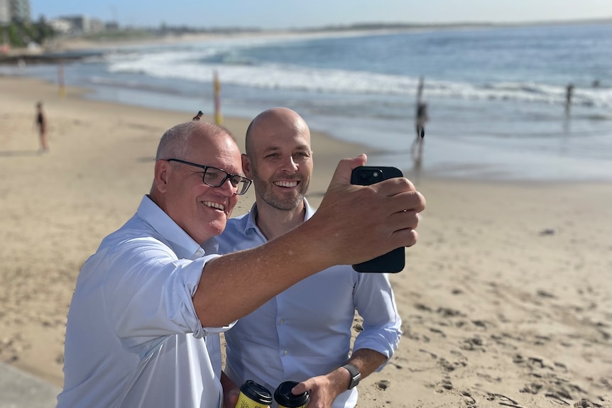 Zwei Männer in blauen Hemden fotografieren am Strand