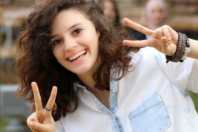 Aiia Maasarwe smiles and holds the two-fingered peace sign up with both hands.