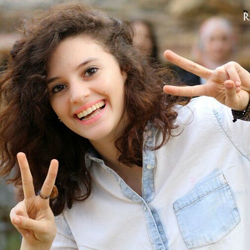 Aiia Maasarwe smiles and holds the two-fingered peace sign up with both hands.