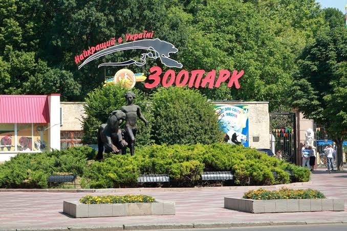 The outside of a zoo with statues and a sign in cyrillic script