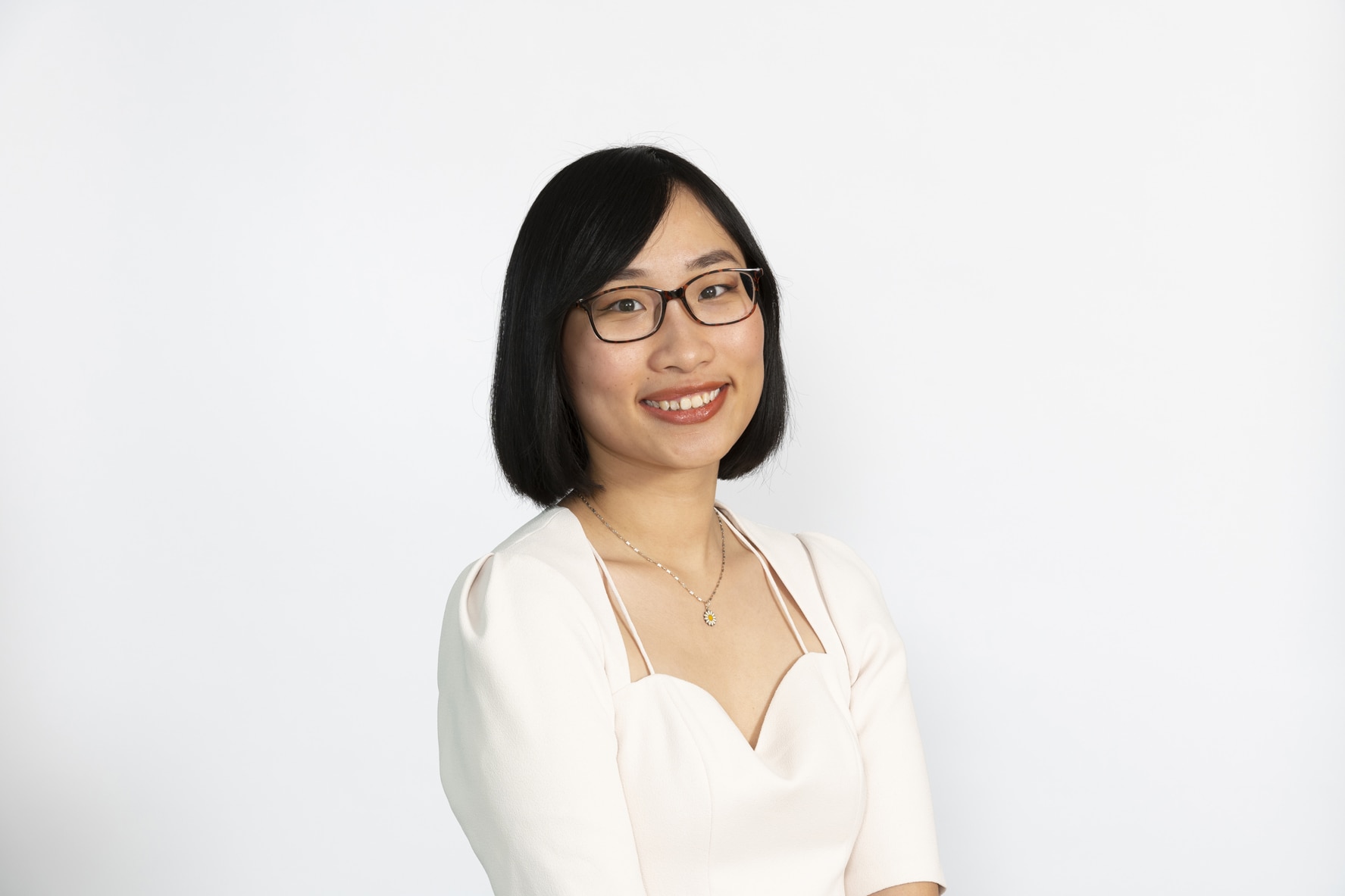 Uma mulher está usando óculos e uma blusa branca.