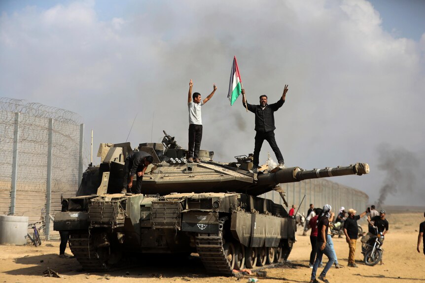 Palestinians wave their national flag on top of a captured Israeli tank. 