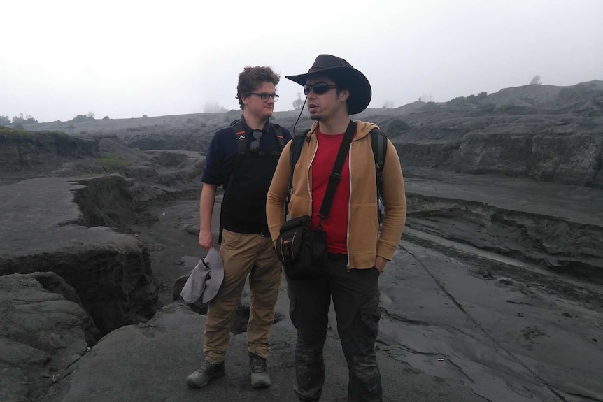 Two men standing on a mud plain in Indonesia.